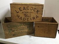 Three vintage wooden crates grouped together, showing front and side views with printed branding and markings.