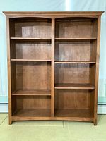 Front view of the wooden double bookcase with two sections and four shelves each.