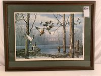 Full view of framed art showing waterfowl in flight near trees and water, wood frame with glass and green matting.