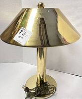 Front view of the brass table lamp with conical shade and base, showing the full height and reflective brass finish.