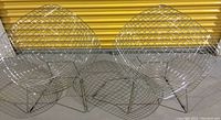 Front view of two chrome-plated diamond wire lounge chairs side by side against yellow storage door