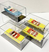 Four die-cast metal convertible toy cars in clear acrylic display cases with black bases arranged together, showing their colors and styles.