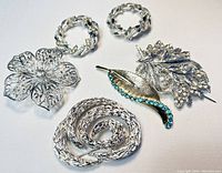 Overview photo showing all six brooches arranged flat on white background highlighting crystal details and variety of designs