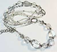 Clear focused image showing faceted large and small crystal beads, freshwater pearl beads on multi-strand, and silver clasp with marking.