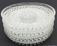 Stacked view of 4 clear glass coasters with textured glass bead pattern.