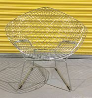 Front view of a chrome wire diamond lounge chair showing diamond pattern mesh seating and backrest with angled base legs and black end caps.