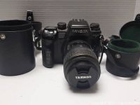 Front view of MINOLTA Dynax 9 camera with TAMRON lens and two protective cylindrical leather cases.