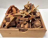 View of the wooden puzzle set inside a wooden compartmentalized box showing various interlocking puzzles made from Thai Raintree wood.