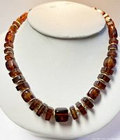 Front view of vintage Baltic amber choker necklace on white display, showing polished amber beads with gold-toned spacers.