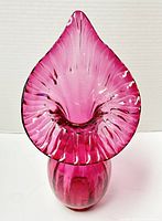 Front view of the cranberry glass jack-in-the-pulpit style vase showing the flared, rippled top and rounded base.
