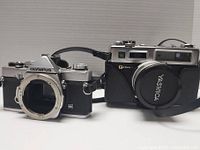 Front view of Olympus OM-1 camera body and Yashica Electro 35 camera with lens attached with Yashica lens cap.