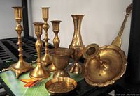 Set of 8 vintage brass items shown on a surface with butterfly designs. Includes candlesticks of varying heights, vases, a dish, and a candle holder.