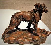 Side view of bronzed metal dog statue showing detailed fur texture and stance.