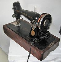 Right side angle showing the Singer logo on the black metal sewing machine mounted on a wooden base with electrical cord.