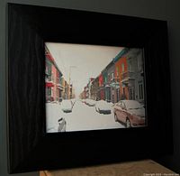 Front view of framed acrylic painting showing a snowy street scene in Montreal with rows of colorful houses and parked cars.