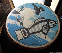 Top view of hand drum showing eagle and salmon native artwork and artist signature.
