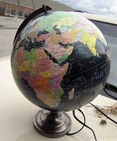 Photo showing detail of the world map on the illuminated globe, focused on Africa, Europe, and Middle East, with metal base and part of power cord visible.