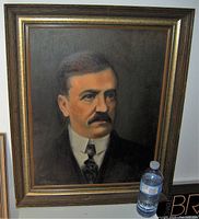 Framed oil painting of a man with a mustache, signed in the lower left, dark background, frontal view