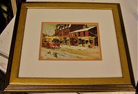 Photo of framed art print "Queen Street" showing streetcar and brick buildings in winter scene with snow. Frame has gold tone and ribbed edges with light wear.