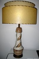 Photo of the table lamp showing the ceramic body with leaf decorations and double-decker beige shade in off state