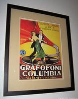Framed vintage poster for Grafoni Columbia gramophones featuring a dancing couple on a record with gramophone horn, mounted on beige mat in dark frame.