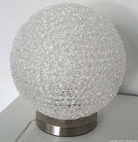 Clear textured spherical glass lamp on metal base, unlit