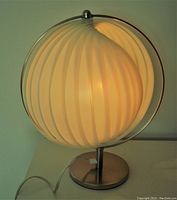 Front view of illuminated lamp showing pleated onion-skin shade and chrome base