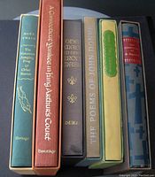 Top view of the six Heritage illustrated classic books showing their spines with titles and heritage branding, in various colors and decorative fonts on cloth bindings and slipcases.