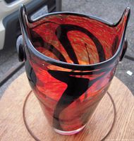 Top angled view showing the swirling red and black pattern on a flared lip glass vase with a clear base, approximately 10" tall.