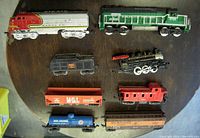 Overhead view displaying all 8 pieces including locomotives, freight cars, tank car, and caboose arranged on a circular wooden surface.