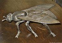 Top side view showing detailed figural bronzed metal fly ashtray with textured wings and body