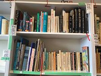 Bookshelves with multiple books on history, religion, and language, showing a wide variety and worn condition