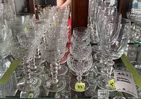 Front view of multiple crystal glasses featuring bubble stems and smooth bowls with round footed bases; some chips visible on rims.