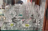 Display cabinet shelf with multiple crystal goblets of varying sizes and designs, showing general lot contents.