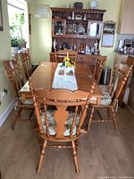 Photo showing the full dining table with six chairs arranged around it in a dining room environment