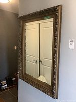 Front view of the framed wall mirror showing the ornate gold frame and reflective surface.