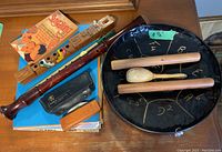 Overview of music books, wooden recorders, maracas, drum with mallets, and a songbook.