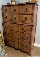 Front view of National Furniture tallboy dresser showing multiple drawers with brass handles and wood finish.