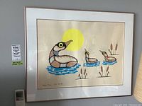 Front view of framed silk-screen print depicting stylized ducks and cattails under yellow sun