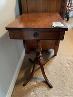 Front angle showing rectangular wood top, drawer and pedestal base with brass feet
