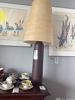 Full view of lamp on wooden table showing base, shade, and surrounding items.