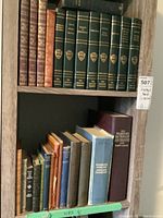 Top shelf with a set of six green books with gold detailing and other vintage books of various colors including brown and blue, plus French and English dictionaries.