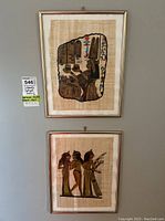 Photo of both framed papyrus art pieces hanging on a wall, showing overall size and framing