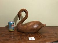 Side view of wooden swan with soda can for size comparison, shows natural wood grain and polished finish.