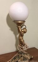 Front angle of cherub lamp with white globe shade, showing wiring and base details