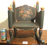 Front view of the child's rocking chair showing painted floral decoration on the backrest and painted turned posts and legs.