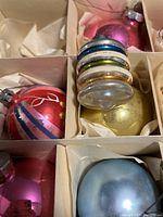 Close-up of vintage glass ornaments showing details, including the stacked ring-shaped ornament with different colors and a pink spherical bauble.