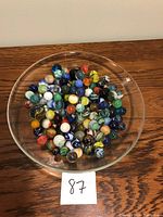 Top-down photo of a glass bowl filled with assorted marbles in various colors and sizes.