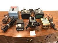 All six transformers and power packs arranged on wooden surface showing front, top and cords