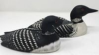 Pair of hand-carved and hand-painted wooden loon bird figurines featuring detailed black and white markings and red eyes, side by side view.